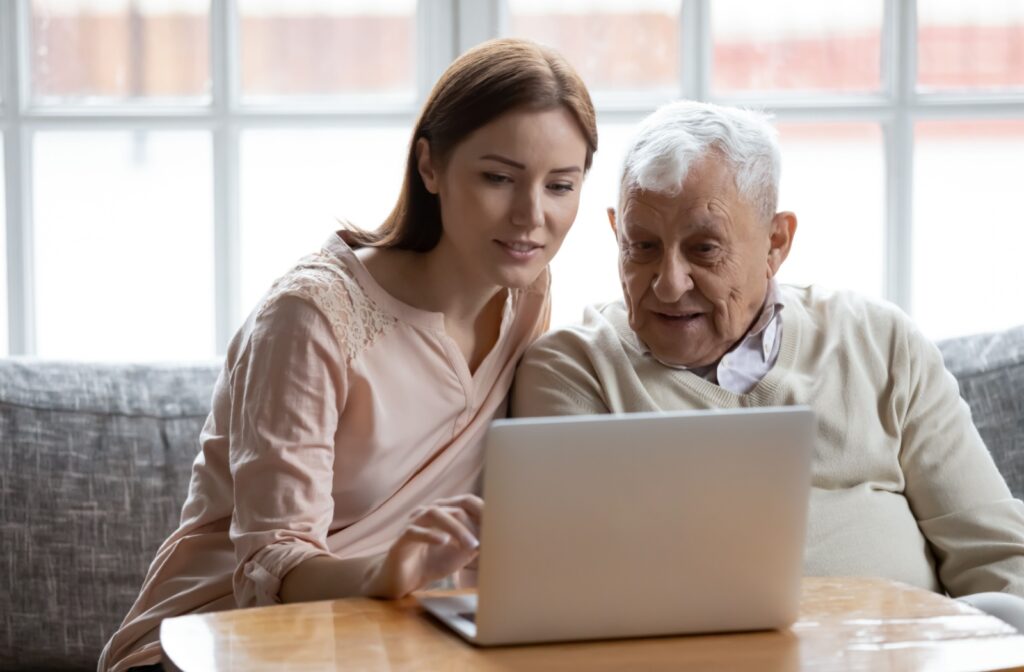 An adult child visiting a parent with dementia, sitting in front of a laptop and explaining the difference options to vote.