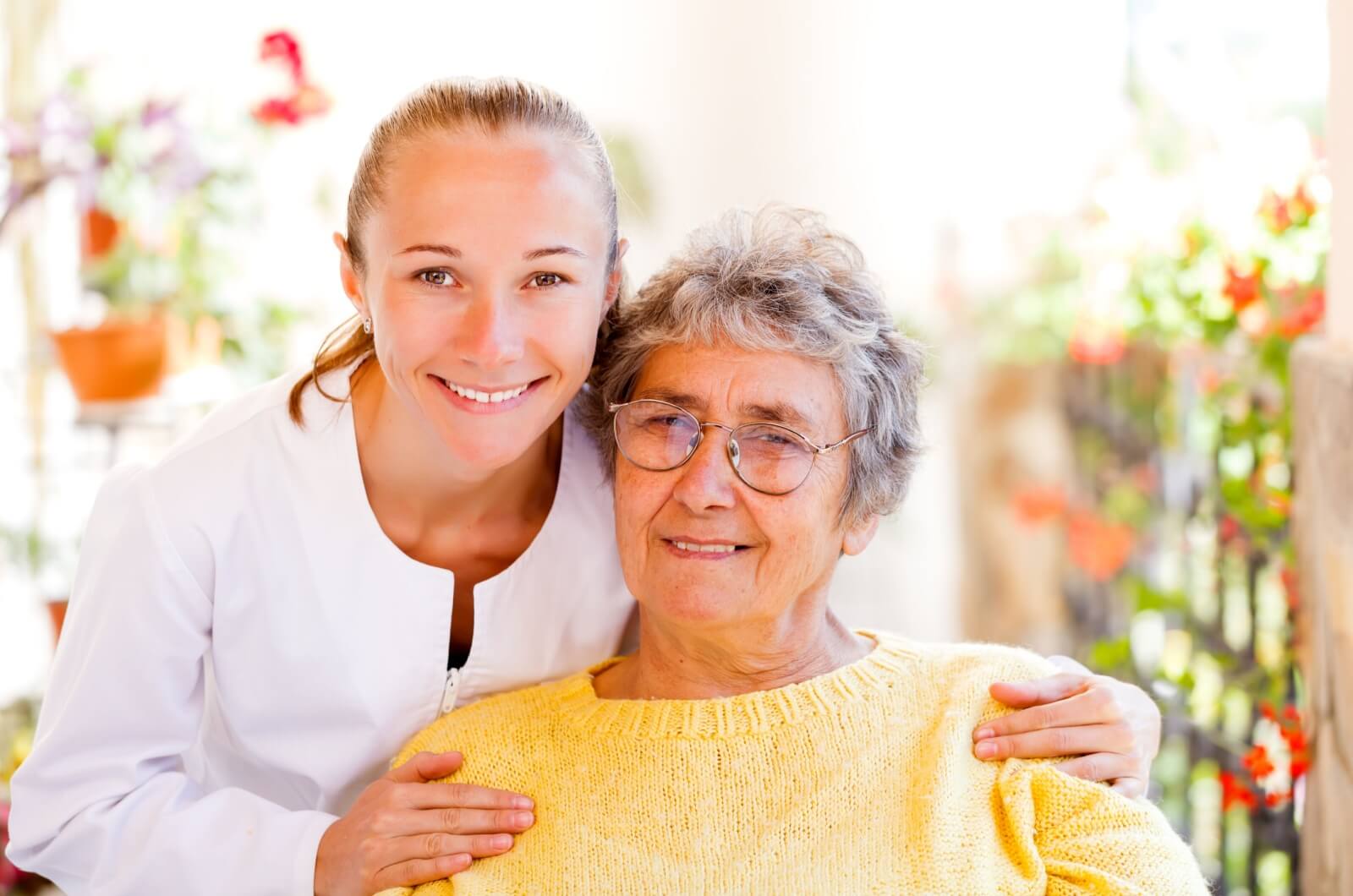 A smiling adult child embracing their parent during a visit in a dementia care community.