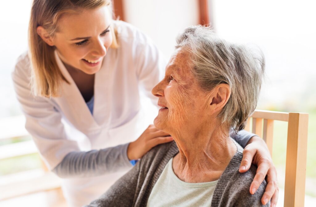 A caregiver smiling while checking on an older adult in a memory care community.