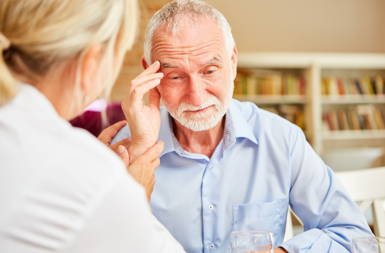 A professional caregiver reassuring a confused older adult after a dementia diagnosis.